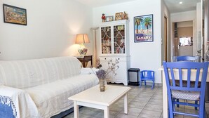 Een woonkamer met een bank, een salontafel, een lamp, een kast en een stoel.
