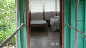 A wooden structure with a thatched roof, leading to a room with a bed and a bench. - Ecoadventure Amazon (Indiana)