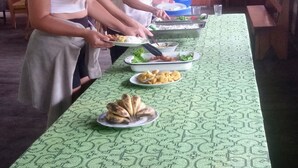 A long table covered with a patterned tablecloth, with food items and people serving themselves. - Ecoadventure Amazon (Indiana)