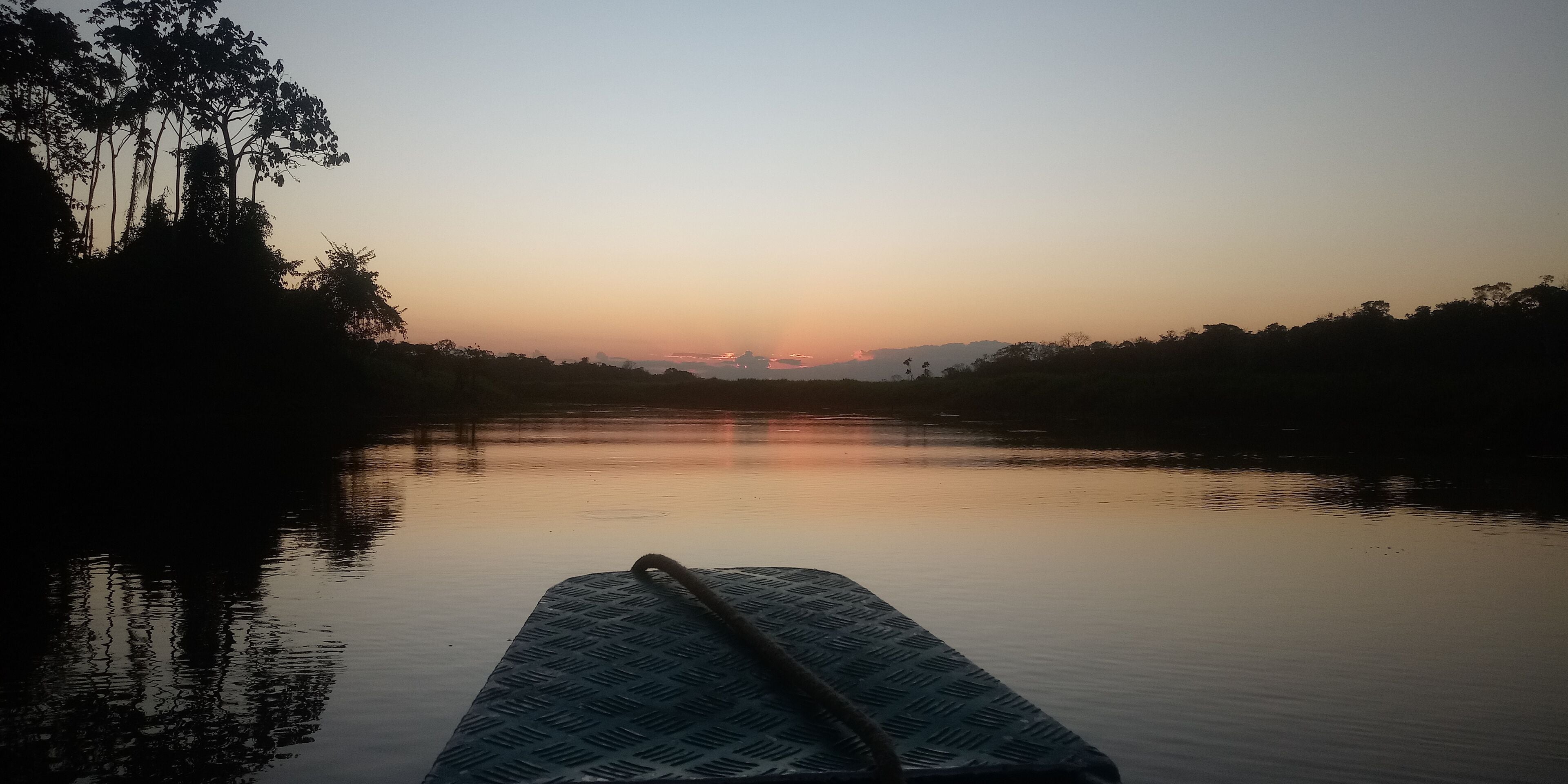A boat on calm water with a sunset in the background.