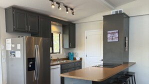 Une cuisine moderne dotée d’un réfrigérateur en acier inoxydable, d’un four encastré et d’un grand îlot central avec des tabourets de bar.