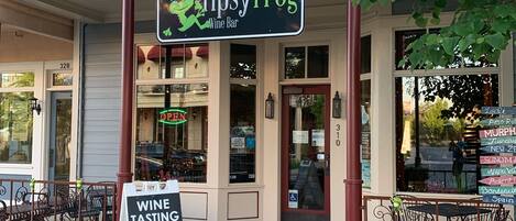 Een wijnbar genaamd "The Tipsy Frog" met terras en een bord voor wijnproeverij.