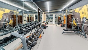 Un gimnasio con espejos, estantes para pesas y equipo de ejercicio.