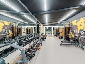 A gym with mirrored walls, weight racks, and exercise equipment. - Atour S Hotel (Guangzhou)