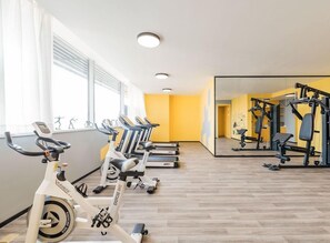 Une salle de sport équipée de vélos d’exercice, de tapis de course et d’appareils de musculation.