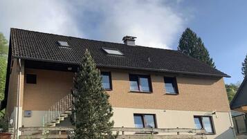 Un bâtiment à deux étages, doté d’un toit recouvert de tuiles, d’une cheminée et d’un escalier menant à l’entrée.
