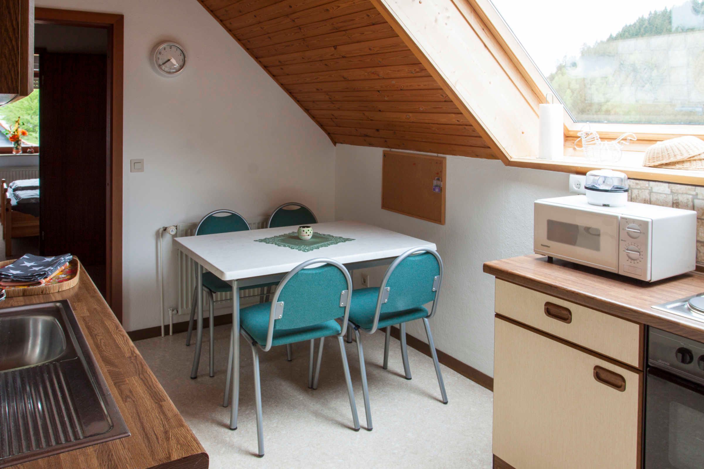 Une cuisine compacte comprenant une table à manger, des chaises, un four à micro-ondes et un évier.