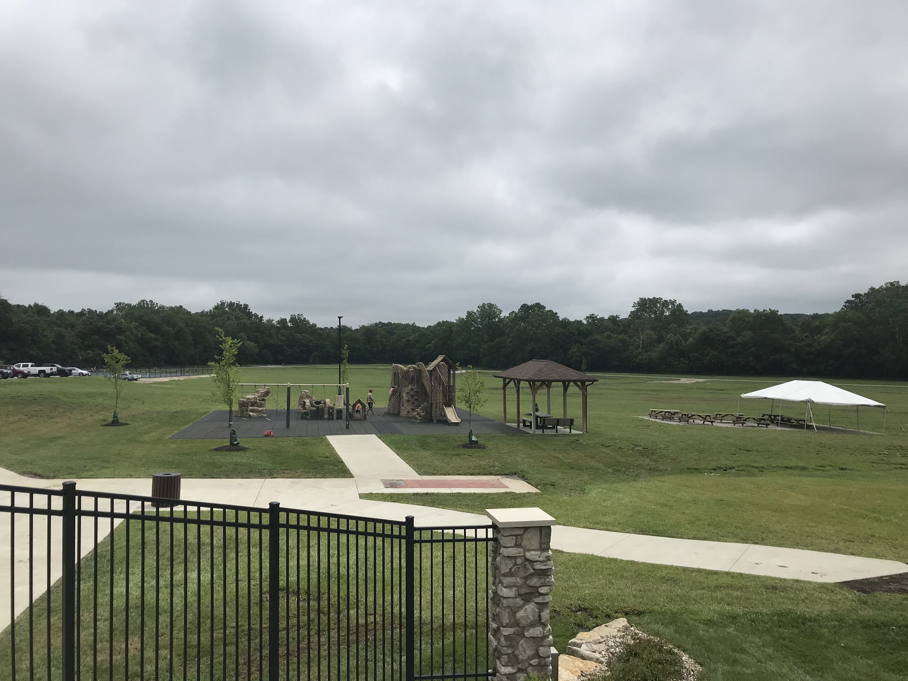 Un parco con un'area giochi, tavoli da picnic e un gazebo.