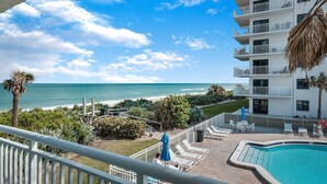 A hotel with a pool, a view of the beach, and a balcony with lounge chairs. - Direct oceanfront 2/2 corner condo with large wrap-around balcony and heated pool (New Smyrna Beach)