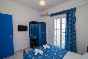 Quarto com cama, guarda-roupa, televisão e janela com cortinas.