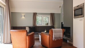 A living room with a sofa, two armchairs, a small table with a bottle, and a fireplace.