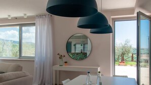 A modern dining area with a white table, a glass cake stand, and a round mirror on the wall. - Vacation home Futura by Interhome (Todi)