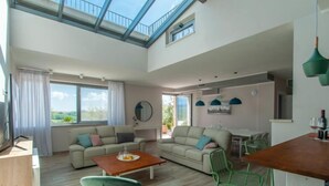 A spacious living area with a high ceiling, a dining table, and a kitchen area. - Vacation home Futura by Interhome (Todi)
