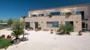 A modern two-story building with a stone facade, large windows, and outdoor seating areas. - Vacation home Futura by Interhome (Todi)