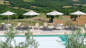 A poolside area with lounge chairs and umbrellas, overlooking a scenic landscape. - Vacation home Futura by Interhome (Todi)