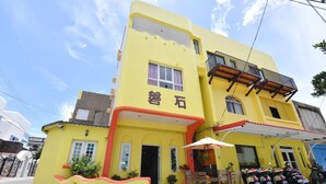 Un edificio amarillo con balcón y una zona de estar al aire libre techada.