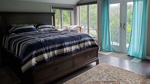 Un dormitorio con una cama grande, cabecera de madera y vista a un balcón a través de una puerta corrediza de vidrio.