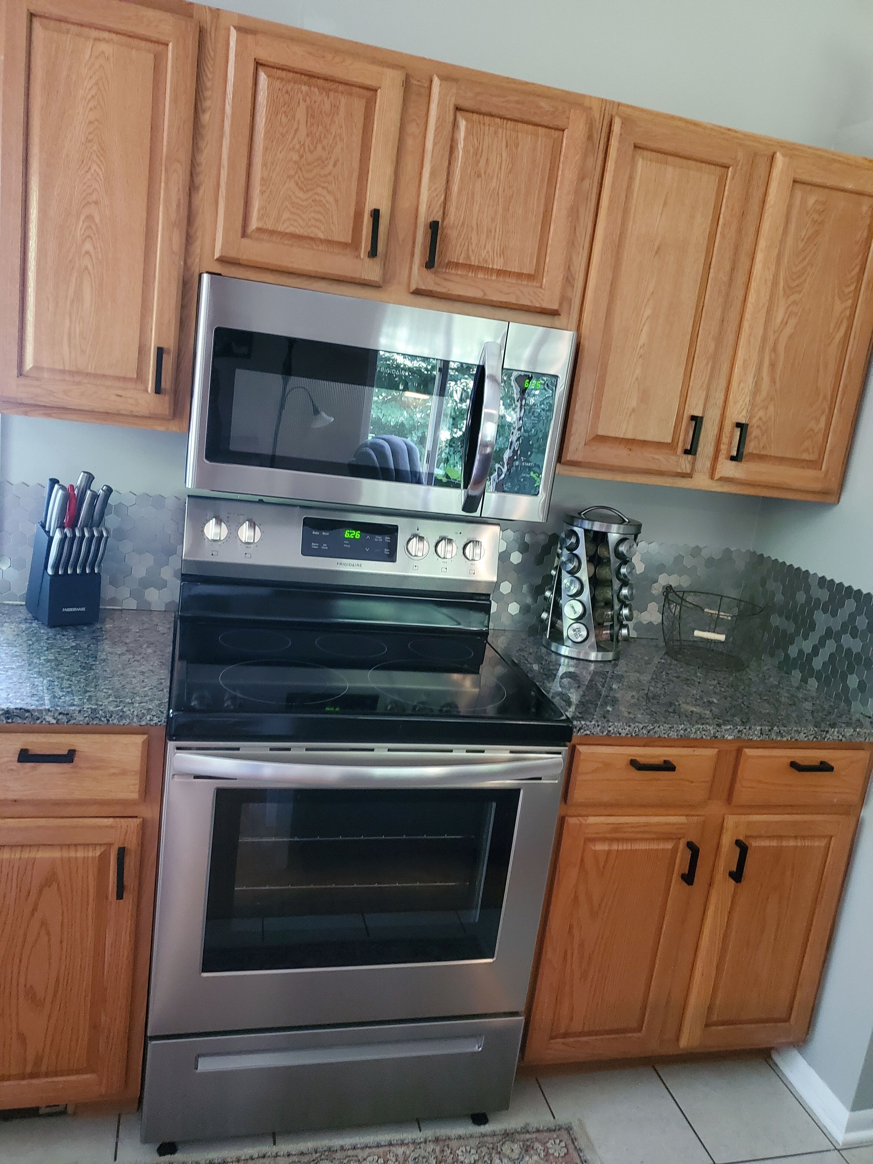 A kitchen with wooden cabinets, a microwave, a stove, and a built-in oven.