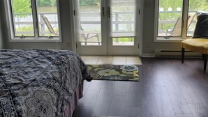 Un dormitorio con cama, una alfombra y vistas a una terraza y árboles.