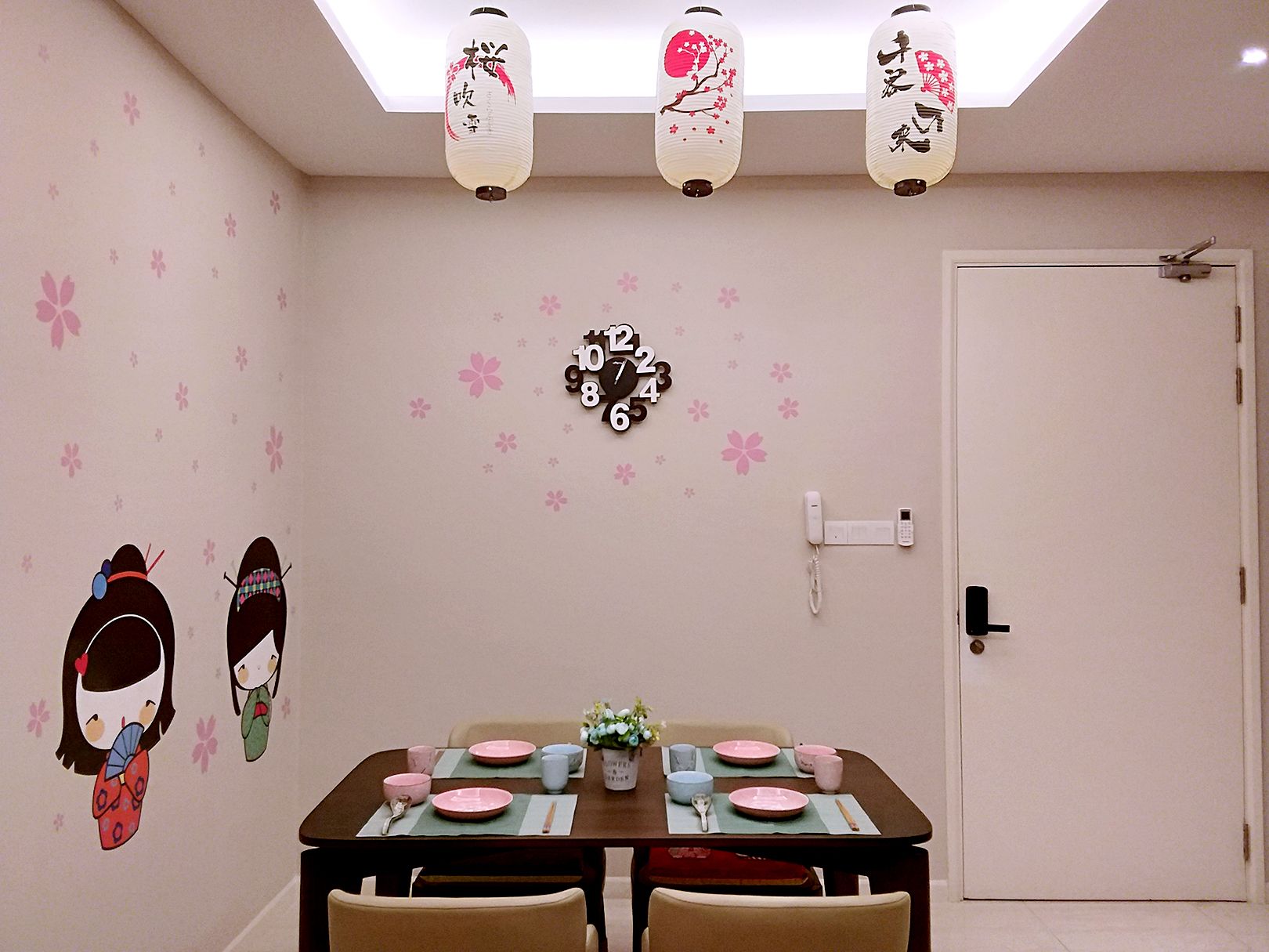 A dining area with a table set for four, a wall clock, and decorative lanterns.
