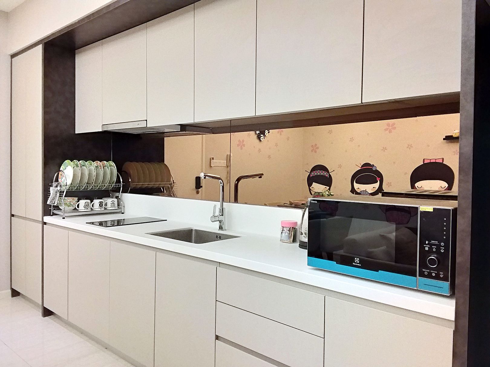 A modern kitchen with white cabinets, a double sink, a microwave, and a dish drying rack.