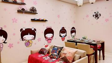 A living room with a sofa, a dining table, and decorative wall stickers.