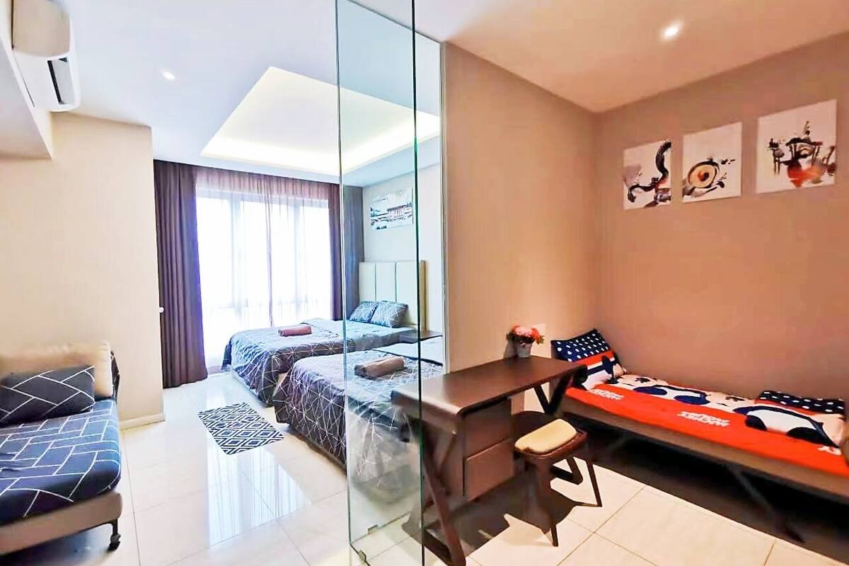 Una habitación de hotel moderna con un separador de vidrio, un escritorio, una cama y un sofá.