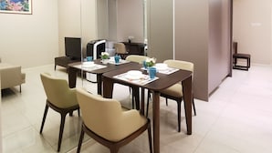 Un comedor moderno con separador de vidrio, televisor y una pequeña mesa con sillas.