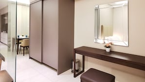 Una habitación de hotel moderna con armario correderas, una mesita de noche con espejo y un pequeño banco.