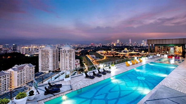 Una piscina en la azotea con sillas de descanso y vista panorámica de la ciudad.