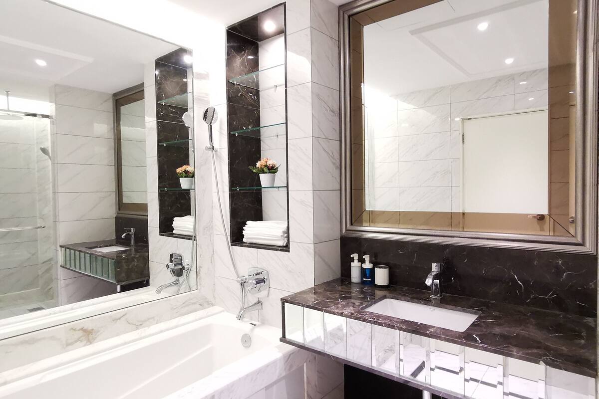 Un baño moderno con una bañera grande, cabina de ducha de vidrio y tocador con lavabo y espejo.