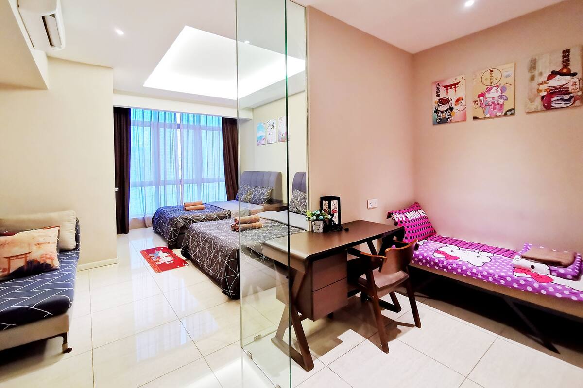 Un dormitorio moderno con separador de vidrio, un escritorio, una cama con ropa de cama estampada y un sofá con diseño de Hello Kitty.