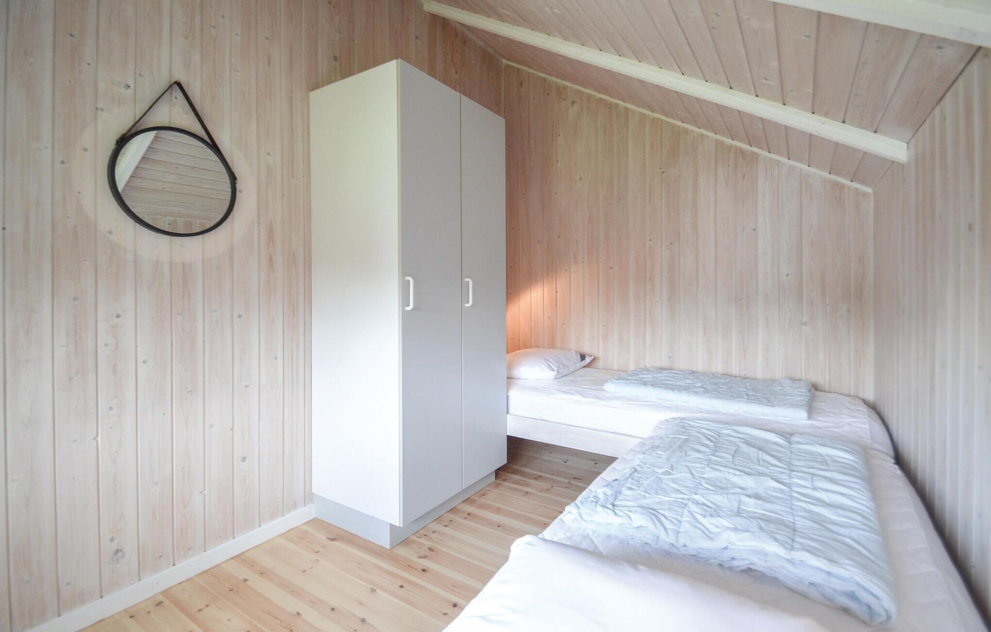 A small, wooden-paneled room with a single bed and a wardrobe.