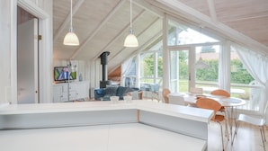 A spacious loft-style room with a high ceiling, large windows, and a built-in fireplace. - 2 bedroom stunning home in Væggerløse (Væggerløse)