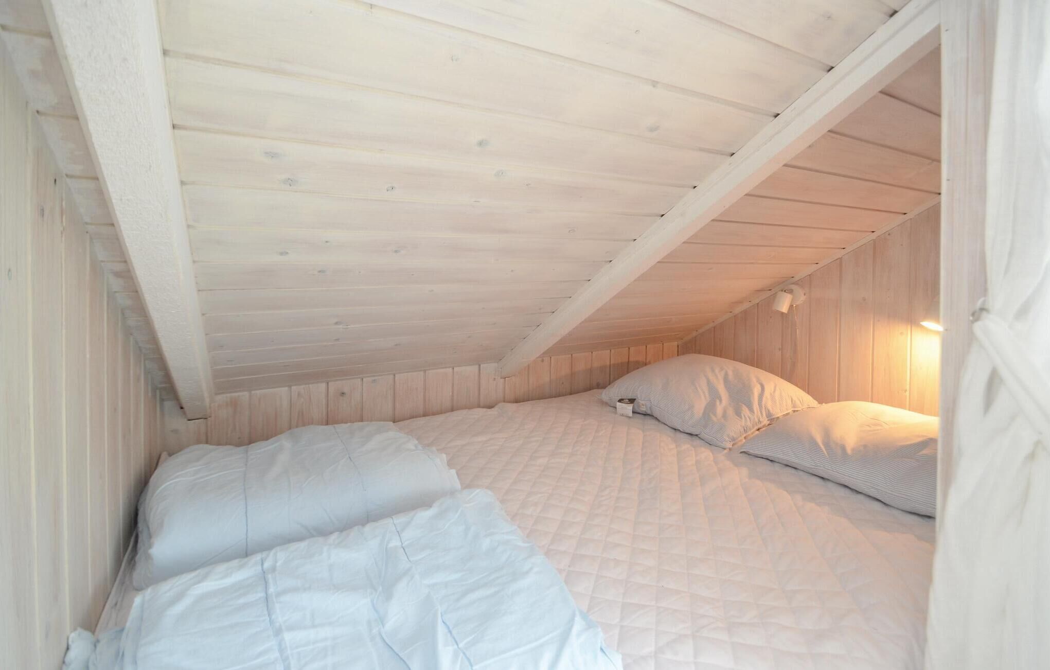 Une petite chambre mansardée, chaleureuse et accueillante, avec deux lits, des murs en bois et un plafond en pente.