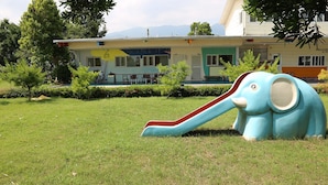 A playground with a slide and a large elephant statue in a grassy area with buildings in the background. - Cai Yeye B&B (Jiaoxi)