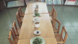 A long wooden table with multiple dishes of food arranged in the center, surrounded by wooden chairs. - Cai Yeye B&B (Jiaoxi)