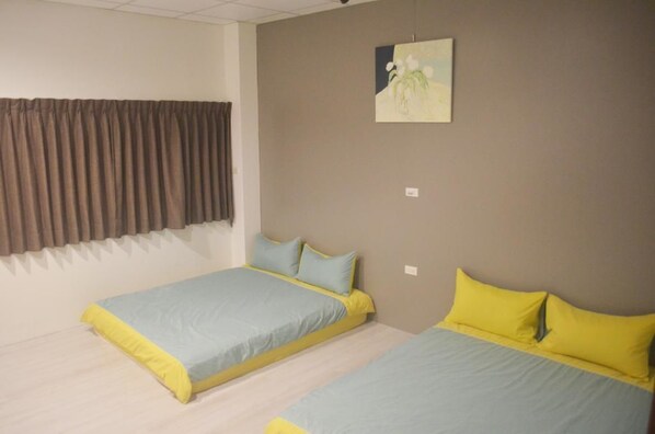 A room with two beds, each with a yellow and blue bedspread. There is a window with brown curtains, and a painting on the wall. - Cai Yeye B&B (Jiaoxi)