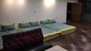 A room with three beds aligned in a row, a wooden floor, and a door to the right. - Cai Yeye B&B (Jiaoxi)