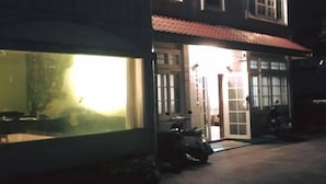 A two-story building with a red-tiled roof and a large window on the ground floor. - Cai Yeye B&B (Jiaoxi)
