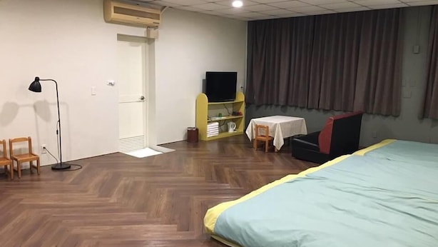A hotel room with a large bed, a desk with a chair, a television, and a wardrobe. - Cai Yeye B&B (Jiaoxi)