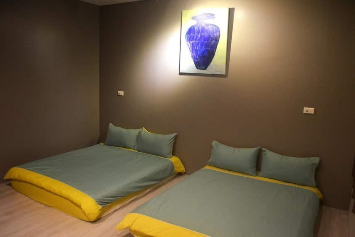 A room with two beds, each with green and yellow bedding, and a single framed artwork on the wall.