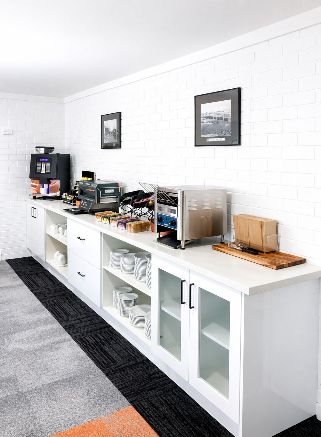 A kitchenette with a coffee machine, a microwave, and storage cabinets.