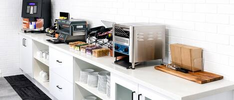 A kitchenette with a coffee machine, a microwave, and storage cabinets.