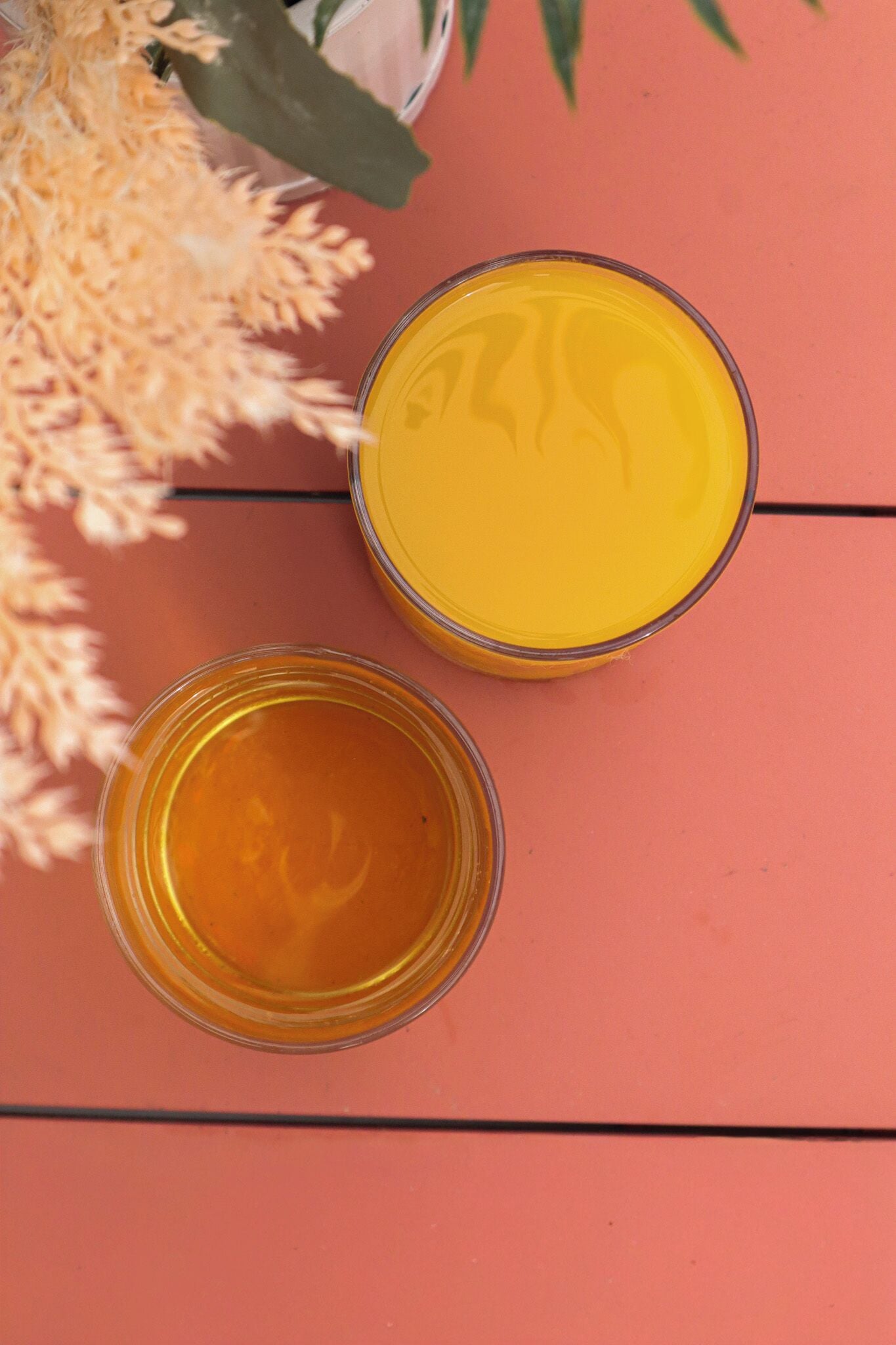 Dois recipientes de vidro com líquido amarelo sobre uma superfície de madeira.
