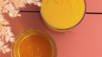 Dois recipientes de vidro com líquido amarelo sobre uma superfície de madeira.