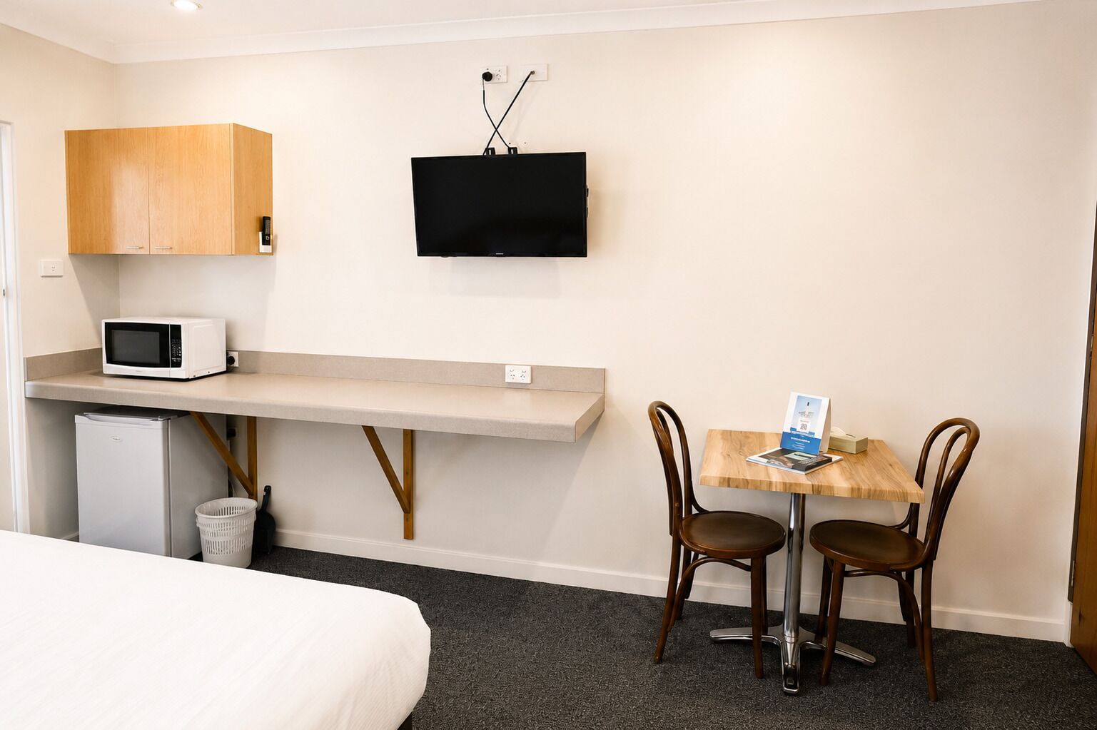 Habitación de hotel con cama, escritorio, computadora, televisor y microondas.