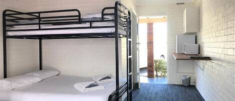Een slaapkamer met stapelbed, bureau en televisie.