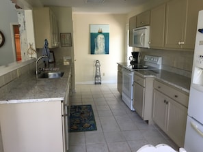 Enjoy cooking in this well-lit kitchen with a central island, microwave, and stove.