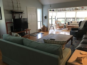 Relax in this spacious living room with a large flat-screen TV, comfortable seating options, and a coffee table.